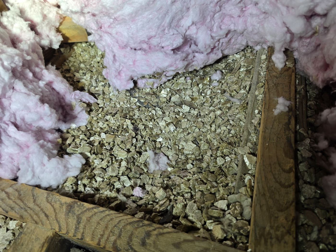 Isolant de vermiculite granulaire entre les solives d'un entretoit, sous de la laine rose